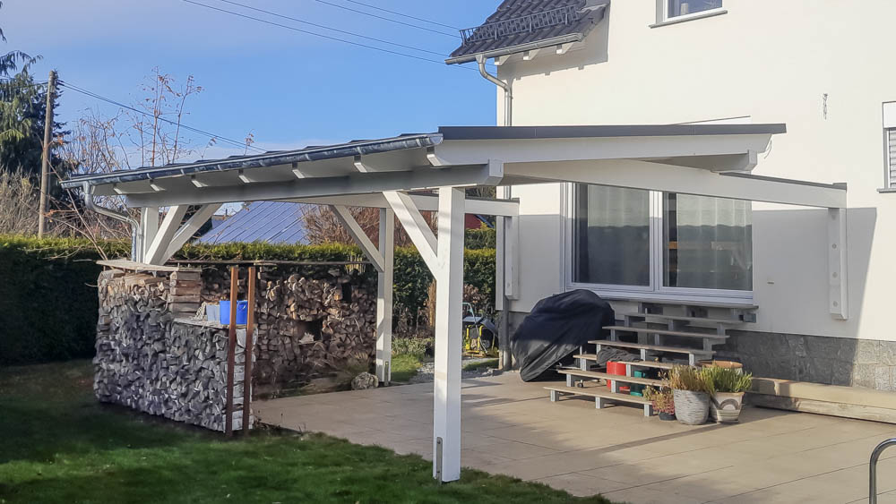 Terrassenüberdachung aus Holz mit Stehfalzeindeckung Weiße Terrassenüberdachung aus Holz