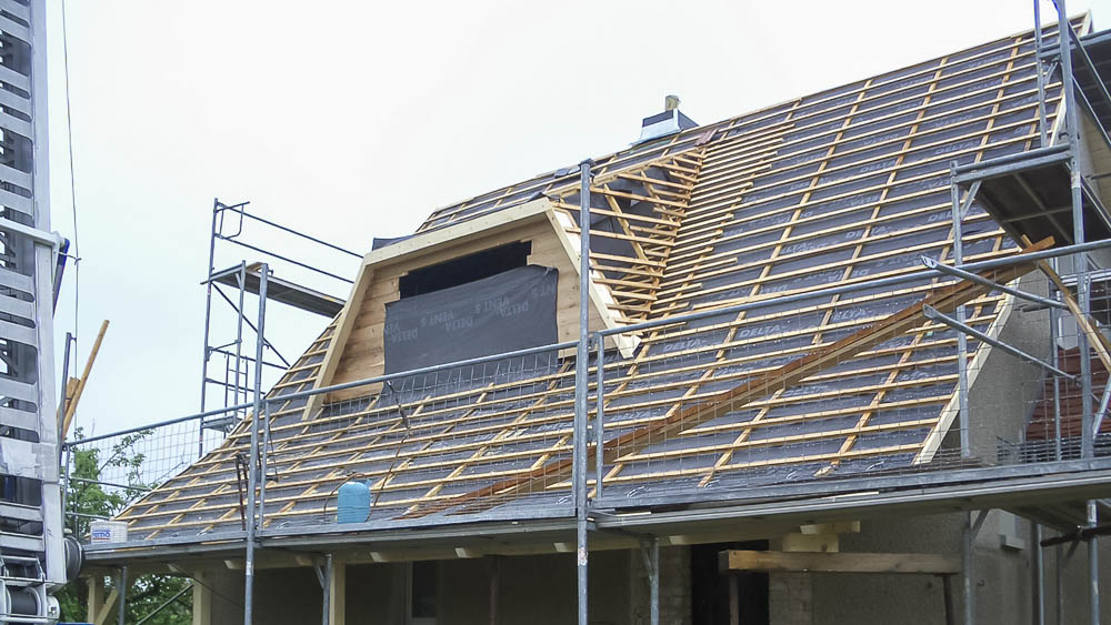 Dacheindeckung mit Einbau einer Dachgaube Ungedecktes Dach mit sichtbarer Lattung und Gaube