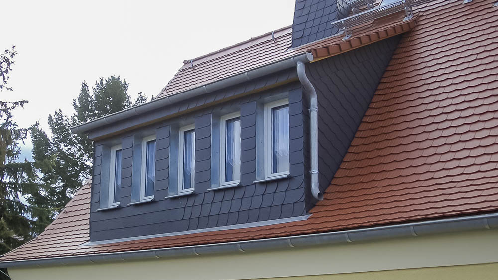 Biberschwanzeindeckung und Gaubenverkleidung mit Bogenschnittschablonen Rotes Biberschwanzdach mit dunkler Gaube