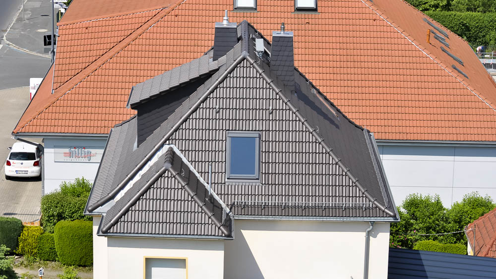 Eindeckung eines Wohnhauses mit Doppelmuldenfalzziegeln Anthrazitfarbenes Steildach auf einem Wohnhaus