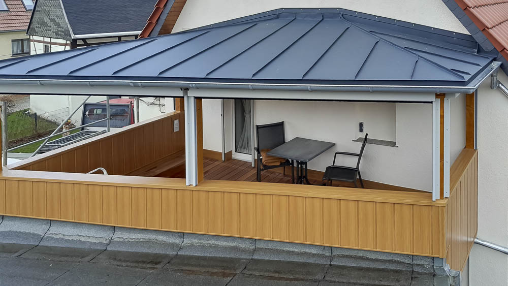 Holzbalkon mit Doppelstehfalzeindeckung und Brüstungsverkleidung mit Prefa-Sidings Holzbalkon mit dunklem Blechdach und Blechverkleidung in Holzoptik